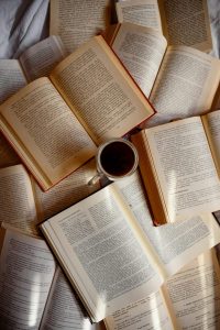 Top view of scattered open books with a cup of coffee in the center.